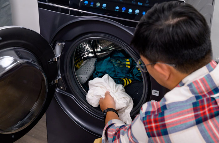 Cho áo quần vào máy giặt rồi đóng nắp máy