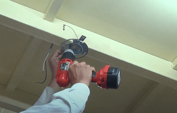 Dùng khoan và máy bắn vít để treo nắp quạt đảo trần lên trần nhà